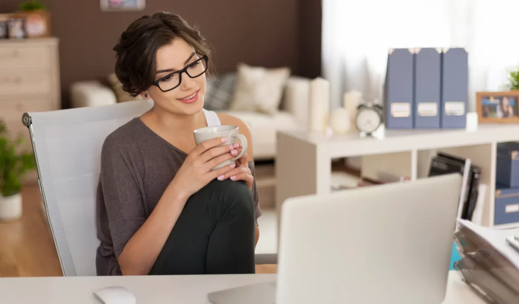 attractive-woman-looking-laptop-while-drinking-coffee-home